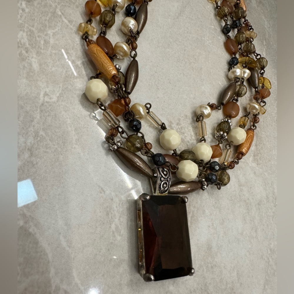 Multi-strand beaded necklace with a touch of brown and green hues.